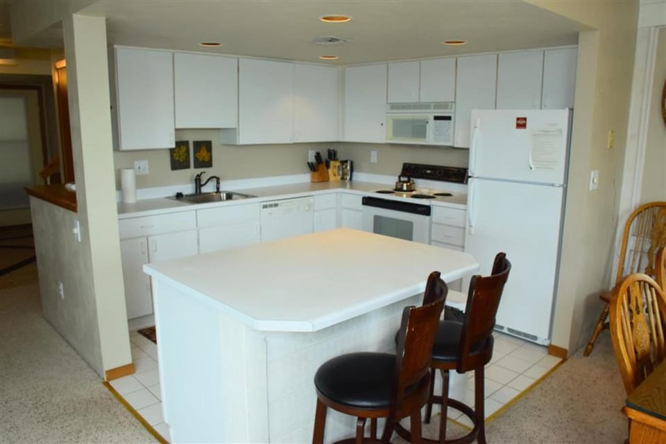 Fully equipped kitchen featuring modern appliances and a central island with bar seating for casual dining.