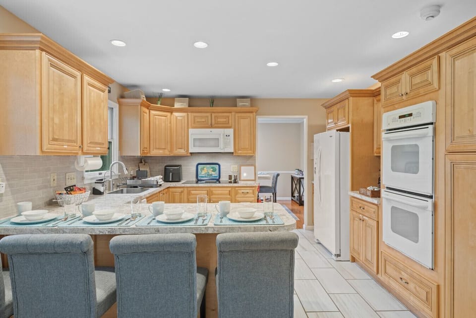 Kitchen | Spacious and bright with wood cabinetry, modern appliances, and island seating.