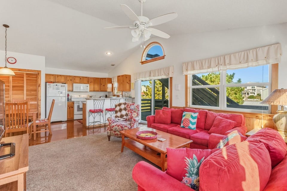 The open-concept living room features cozy seating, coastal décor, and a flat-screen TV, creating a comfortable gathering space for the whole family.