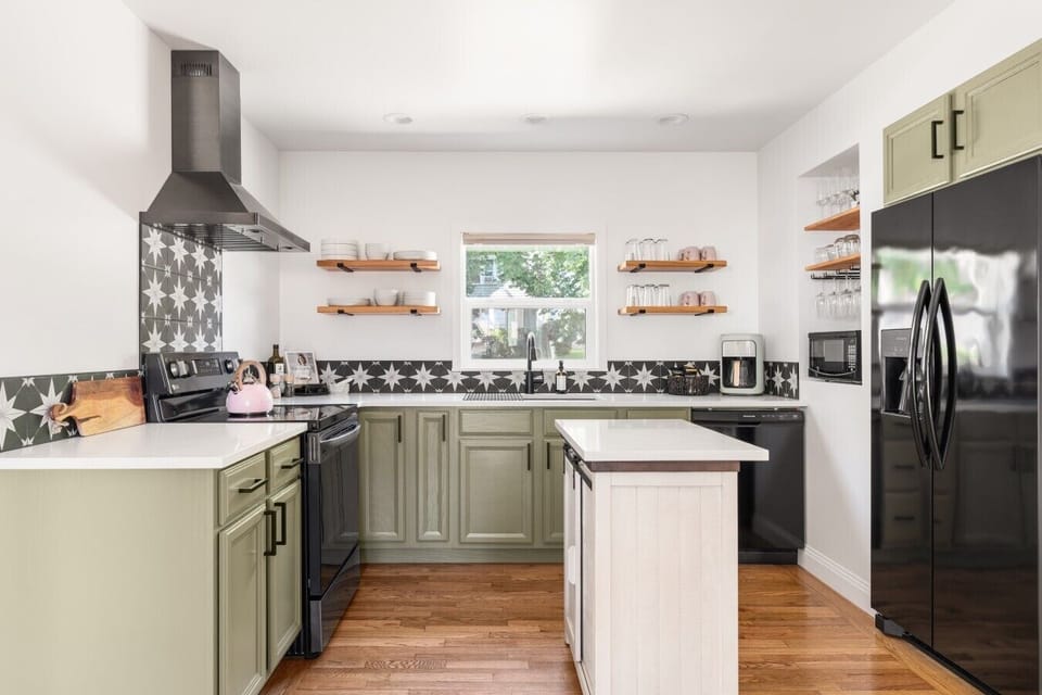 Bright, fully updated kitchen with quartz counters, green cabinetry, and an inviting center island.