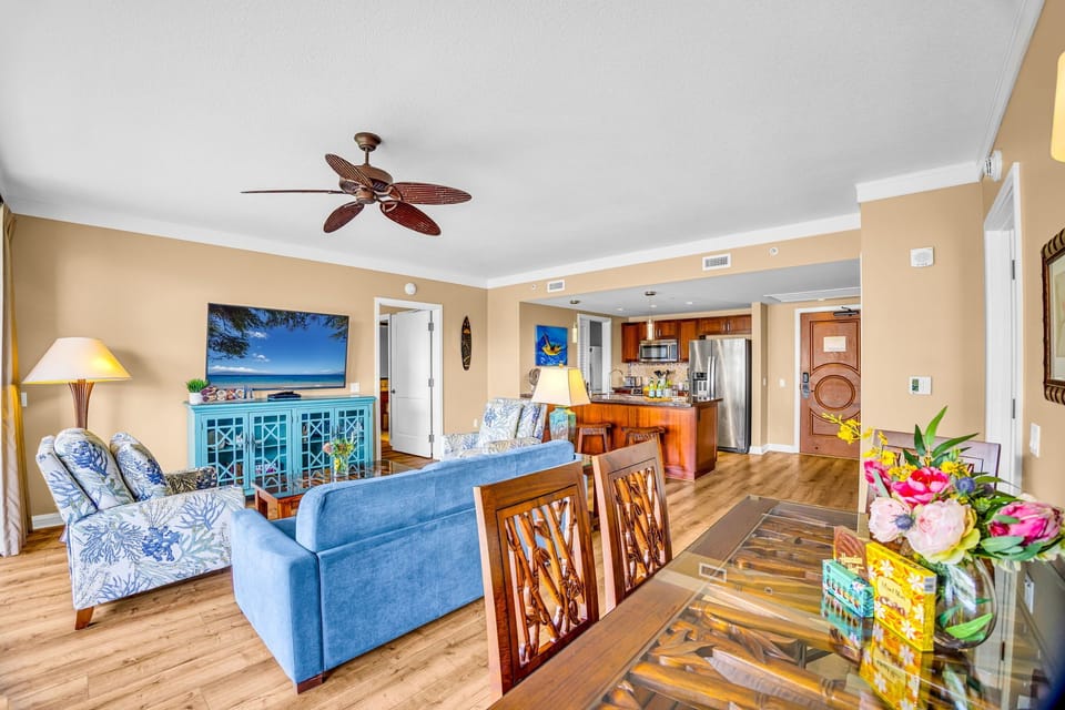 Living room with a large sofa, two comfy chairs, ceiling fan, and direct access to the lanai for a breezy, connected layout.
