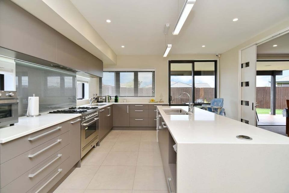 Kitchen – Designed for Entertaining  Spacious kitchen featuring two sinks, island with bar stools, air fryer, and extra-wide oven — ideal for families and guests who love to cook together