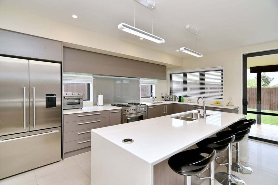 Kitchen – Modern & Functional  Large, well-equipped kitchen with two sinks, island bench, and bar seating. Includes an extra-wide oven and air fryer — perfect for group cooking or family meals.