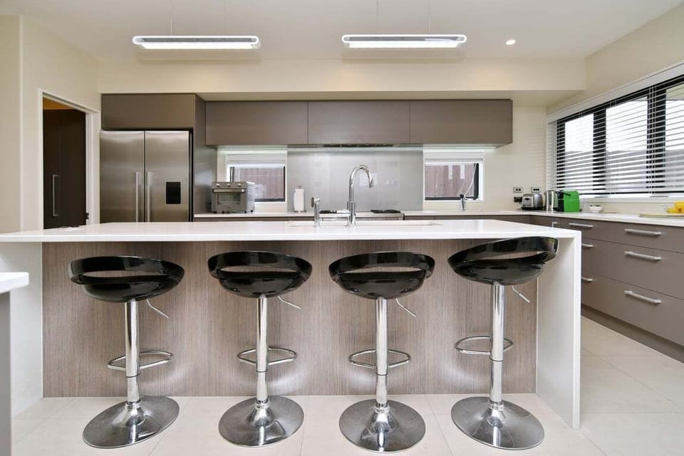 Spacious Kitchen – Fully Equipped & Modern  Bright, open kitchen with two sinks, kitchen island, and bar stools for casual dining. Features an extra-wide oven, air fryer, and everything needed for preparing shared meals.