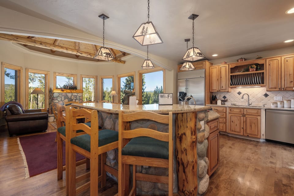 Your rustic kitchen features warm wood cabinetry, stone accents, and mountain views through expansive windows for memorable meal prep.