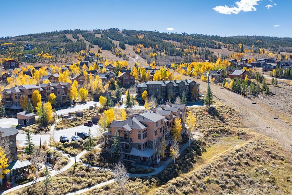 Kicking Horse Palomino 7-302 is a mountain community nestled among vibrant golden aspen trees with ski slopes visible in the distance.