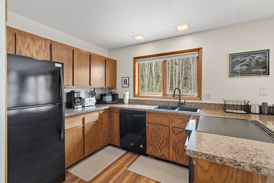Fully-equipped kitchen with stainless steel fridge and forest views.