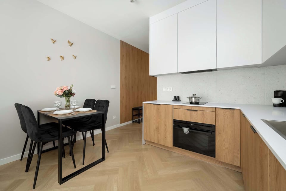 The living and dining areas combined with a kitchen in the background. The neutral palette and wooden accents create harmony.