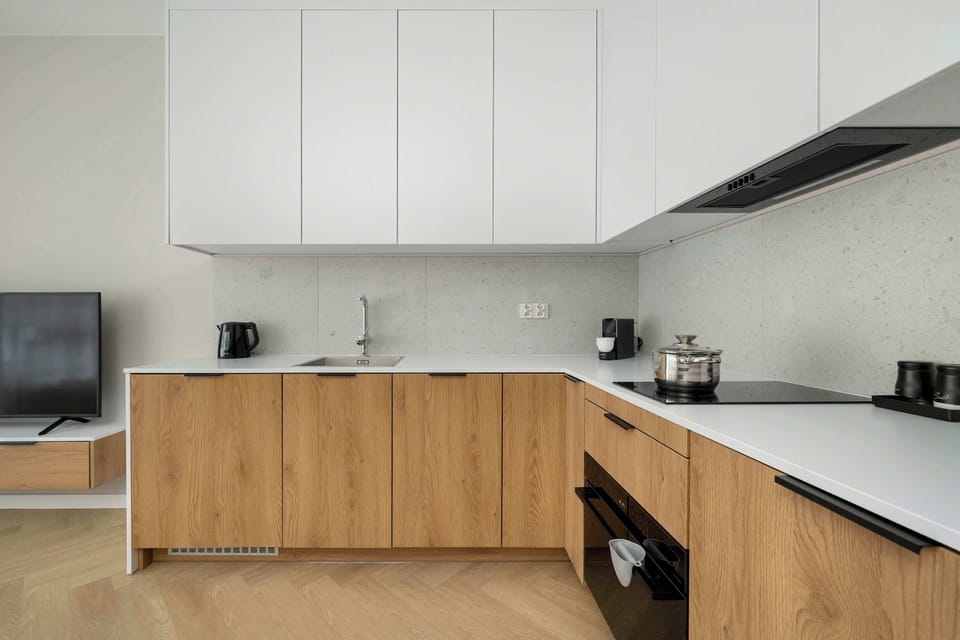 A compact modern kitchen with white upper cabinets and wooden lower units. The sleek layout ensures functionality and style.