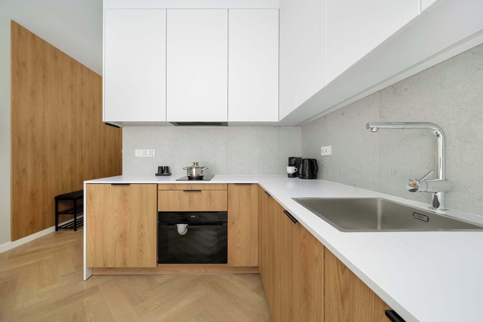 Another angle of the same kitchen showing built-in appliances and a minimalist backsplash. The contrast between white and wood feels modern.