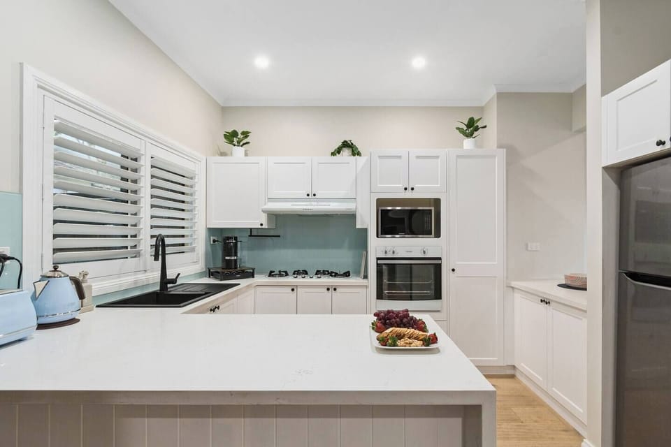 Prepare meals with ease in the bright kitchen, complete with sleek black fittings, a Nespresso coffee machine, and modern appliances designed for effortless home cooking.