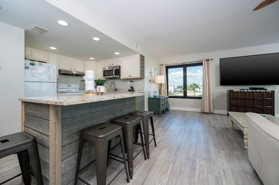 This kitchen features granite countertops, stainless appliances, and a cozy seating area with a view of the beach