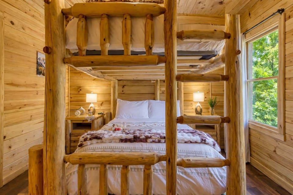 Lower bunk bed with lush linens and rustic log frame—comfortable sleeping space with true cabin character.