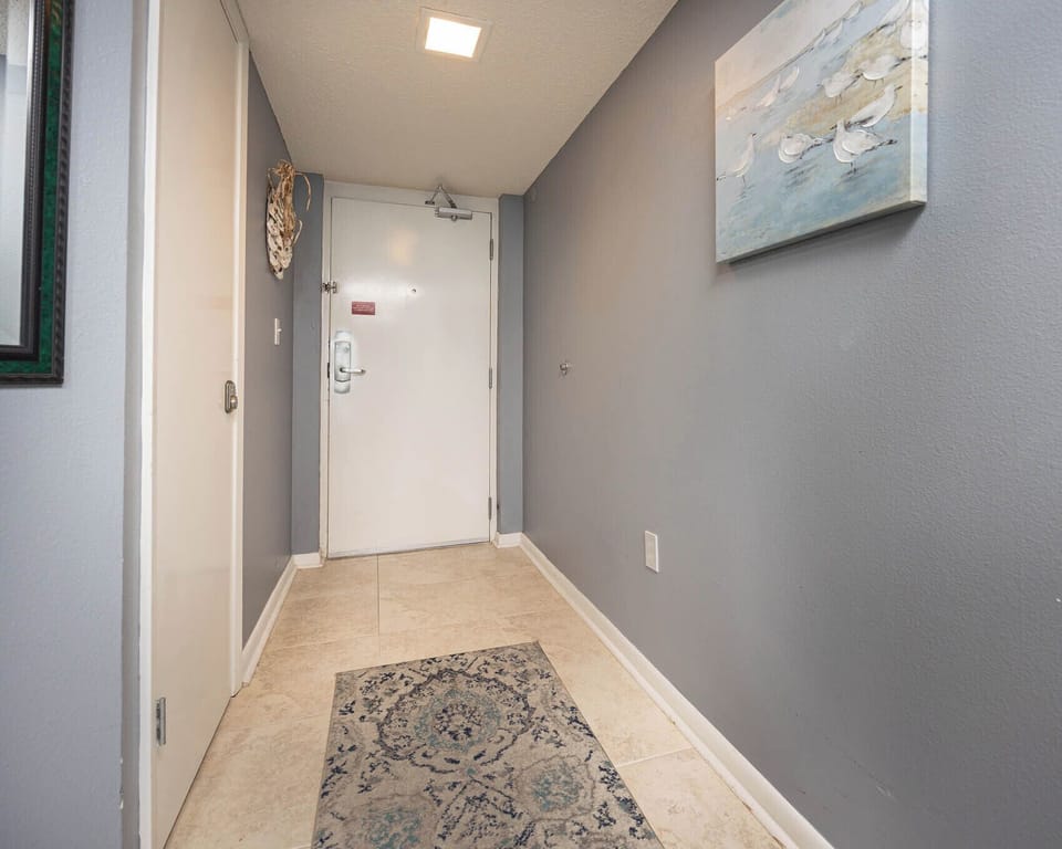 Welcoming entryway features a decorative rug, soft gray walls, and a framed artwork, creating a warm first impression