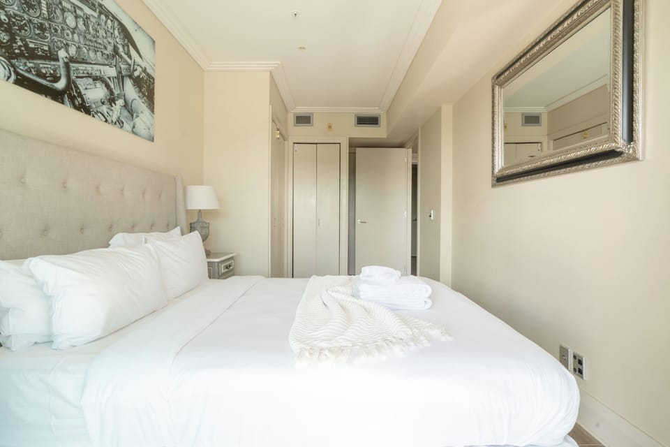 Bright bedroom with tufted headboard and vintage mirror accent