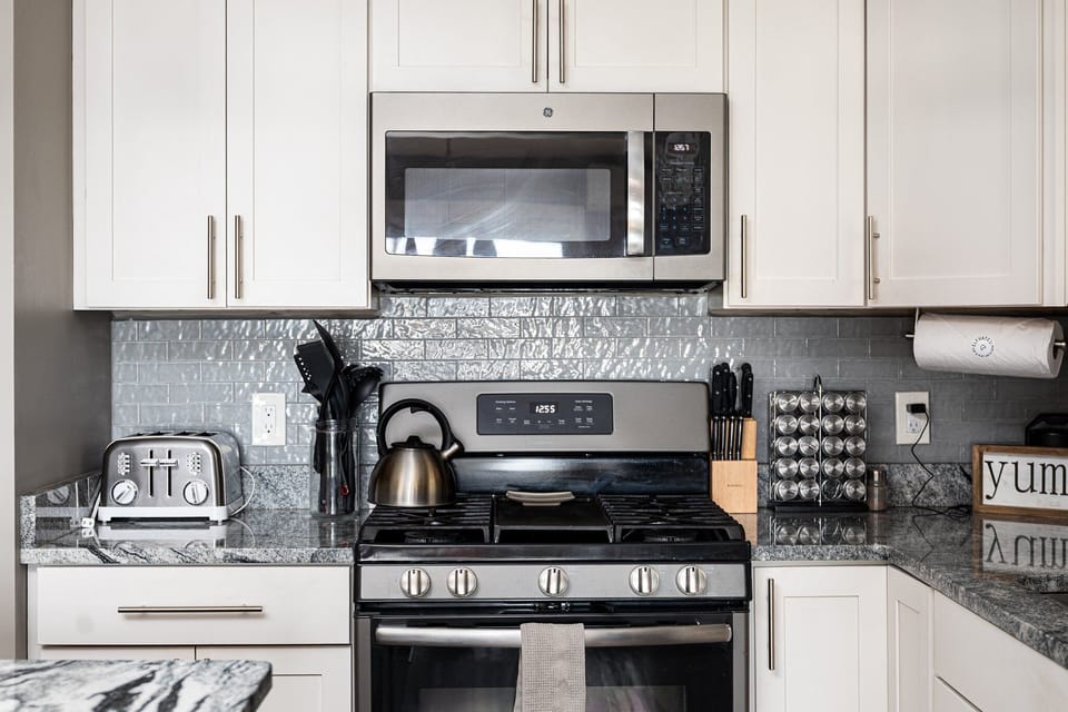 Bright kitchen w/ stainless steel appliances, sleek cabinetry & tile backsplash.