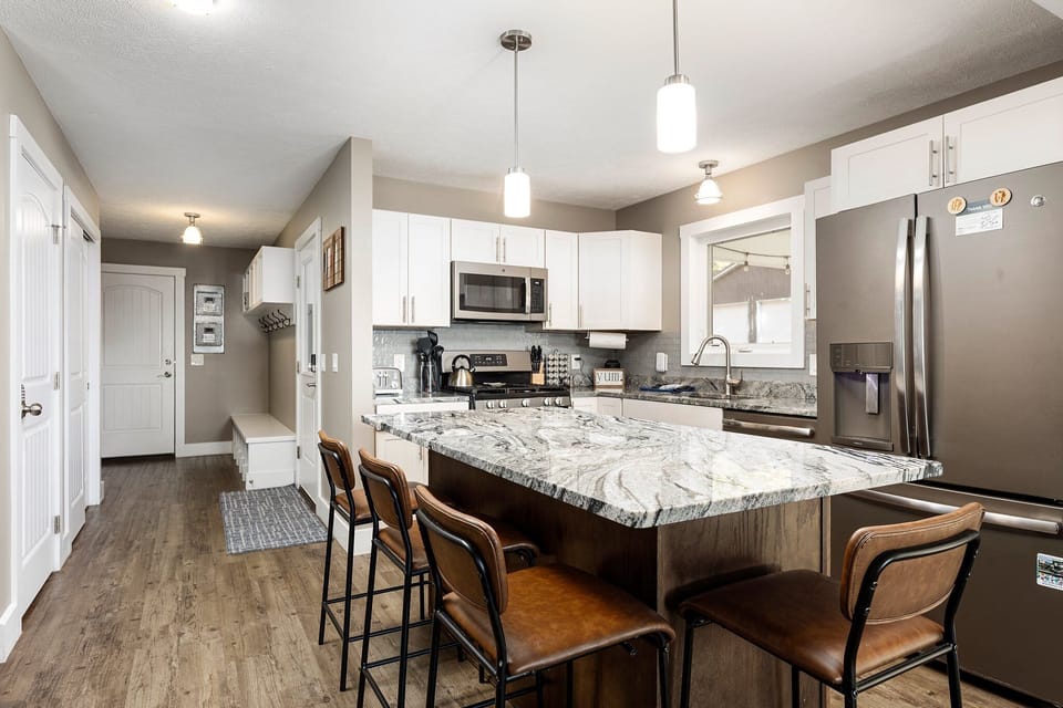 Spacious kitchen island w/ bar stools, pendant lighting & open-concept layout.