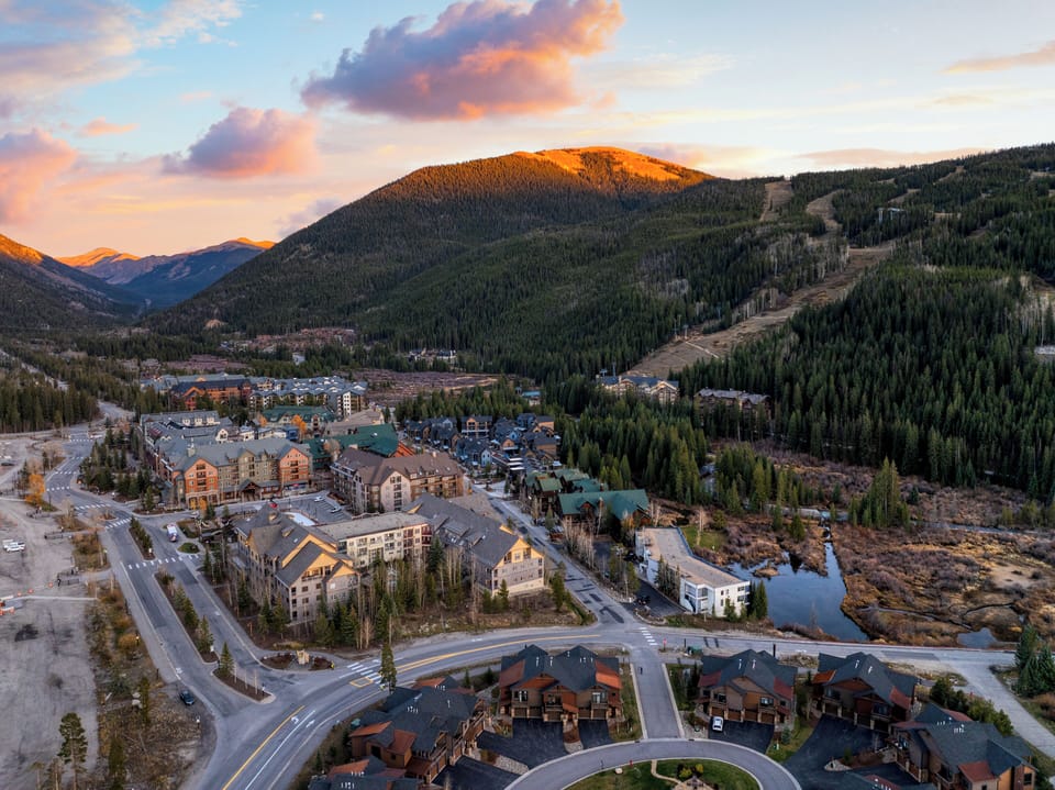Panoramic mountain view with homes below at sunset.