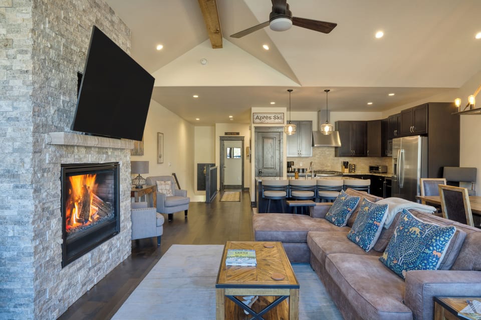 Bright living area with sectional sofa, fireplace, and large TV.