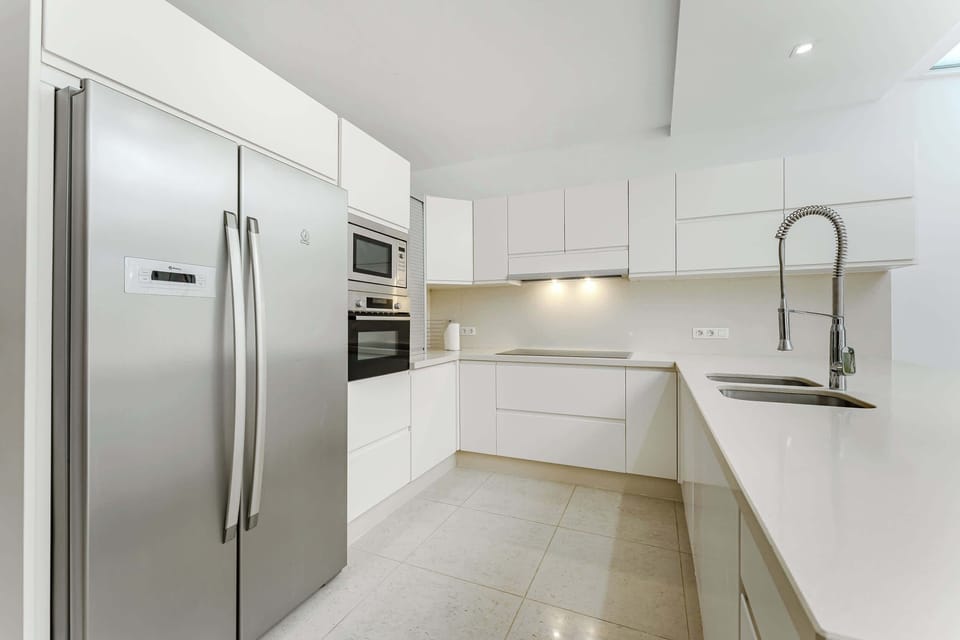 Sleek Modern Kitchen with Full-Size Stainless Steel Appliances, Generous Countertops, and Minimalist White Cabinetry