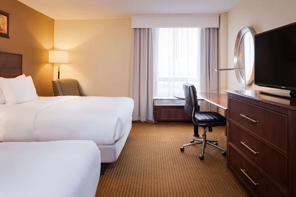 Room with two beds, work desk, and soft daylight view