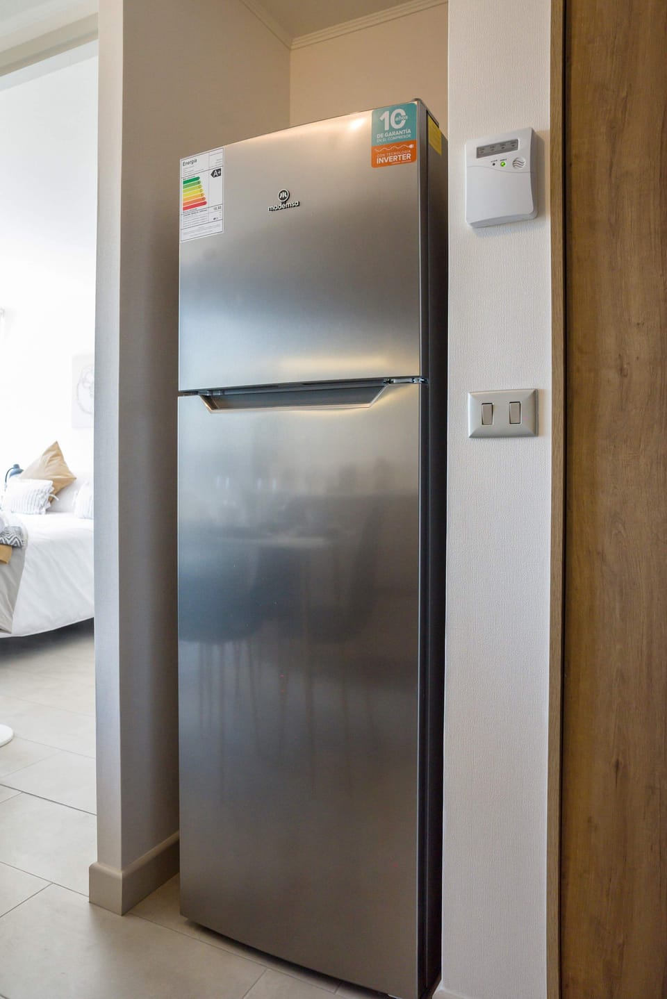 Modern stainless steel fridge in a cozy studio, perfect for your culinary needs.