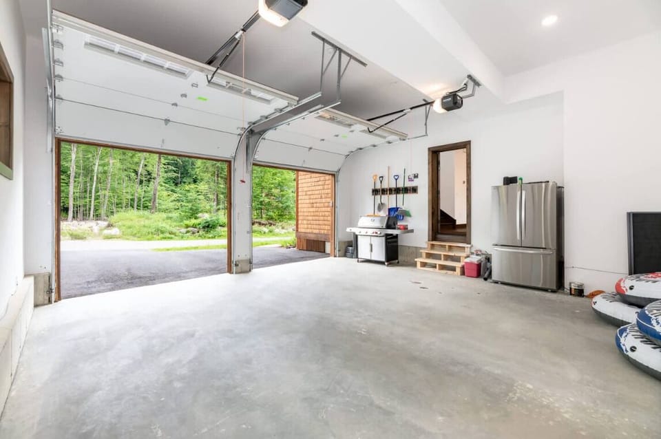 Spacious two-car garage with easy driveway access and plenty of storage space. Features a stainless steel fridge and grill, perfect for extended stays and outdoor cooking prep.