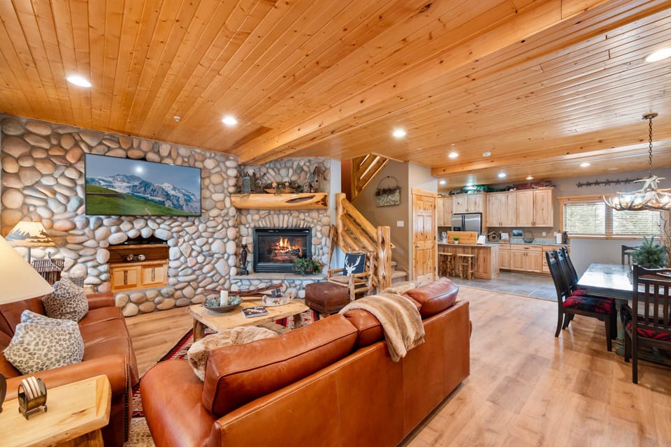 The large living room has a massive stone fireplace, plush leather couches and large smart TV