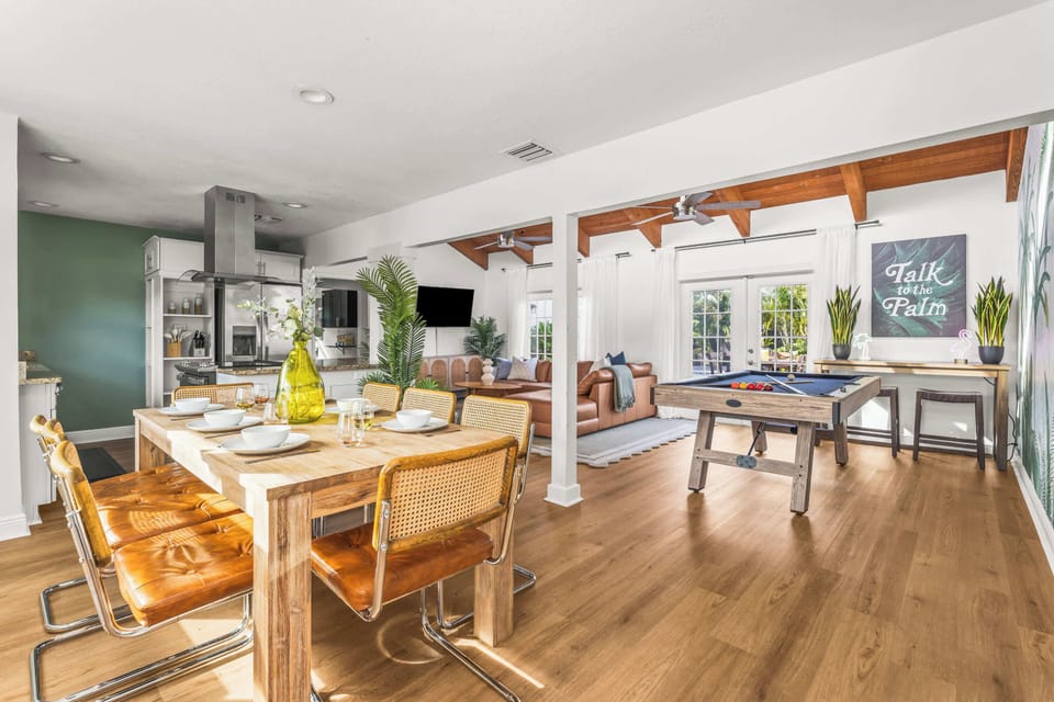 The island kitchen with its stainless range opens straight to the dining table and leather sofa under vaulted beams. - Open Kitchen & Living - The Palm - West Palm Beach, FL