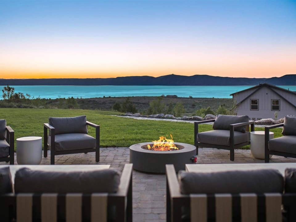 Stunning lakeside patio with modern fire pit, mountain silhouettes, and twilight sky providing a peaceful retreat for gathering and relaxation.