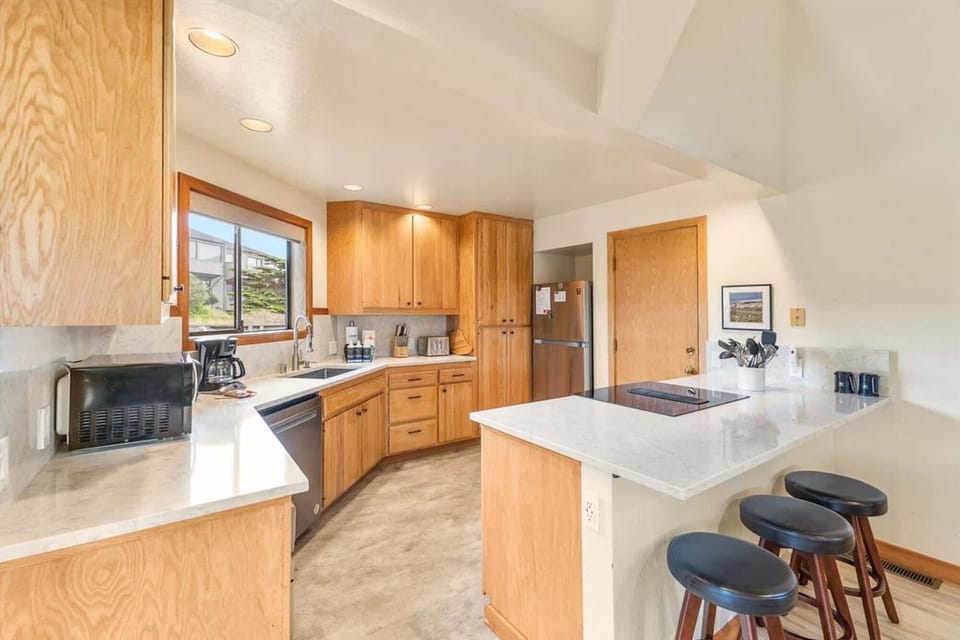 Fully stocked kitchen with bar seating, modern stovetop, and a view.