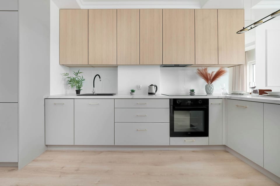 Modern kitchen with light wood cabinets, built-in oven, and minimalist white countertops.
