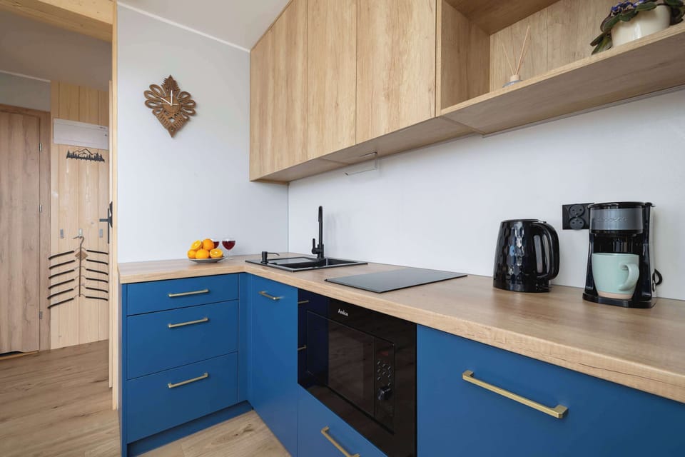 A close-up of a modern kitchen area with a coffee machine, toaster, and kettle set on a wooden countertop.