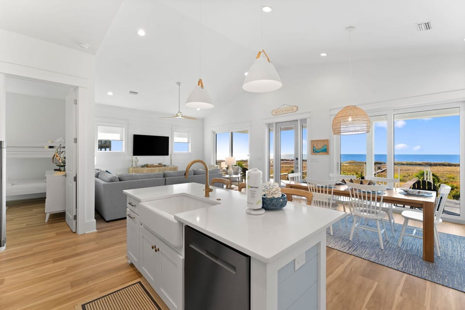 Your bright open kitchen flows seamlessly into the living and dining areas, where ocean views stretch endlessly beyond floor-to-ceiling windows.
