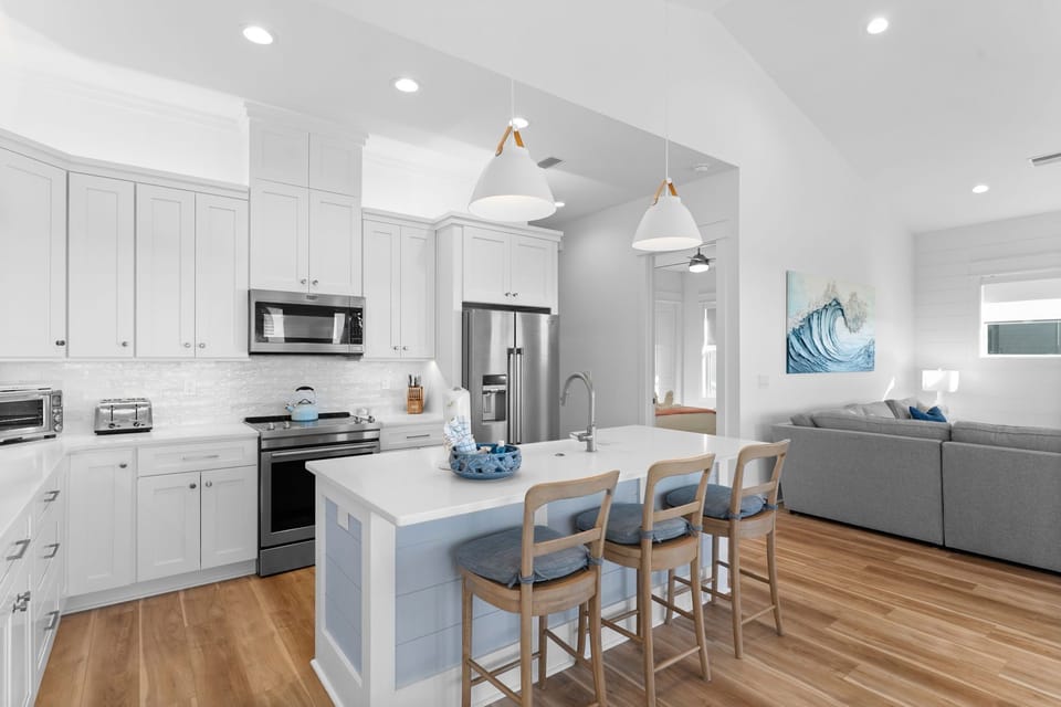 Your bright open kitchen features sleek white cabinets, stainless steel appliances, and a spacious island with seating for casual dining and socializing.