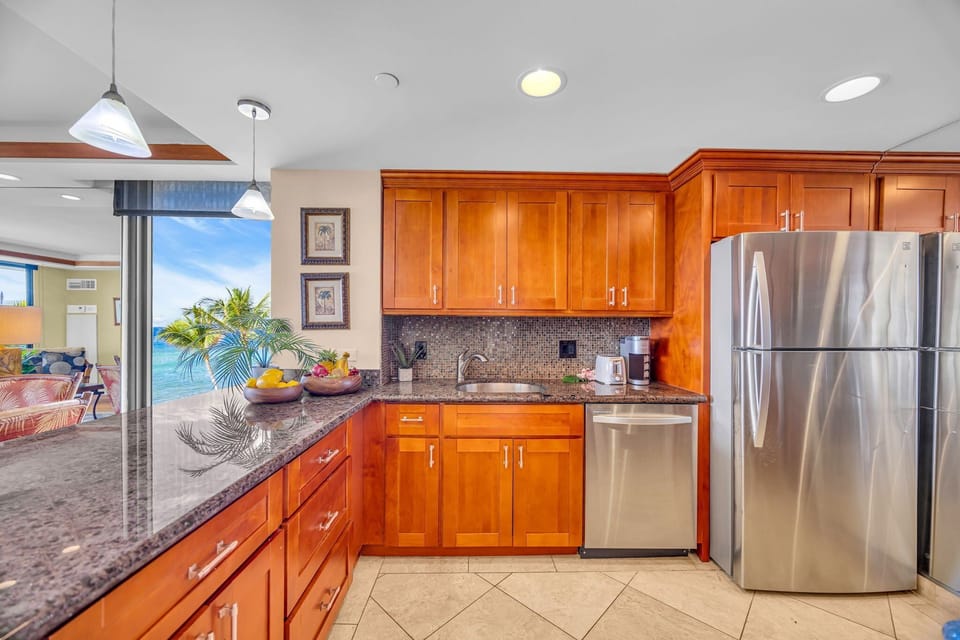 A fully equipped kitchen with granite countertops, wooden cabinetry and stainless steel appliances