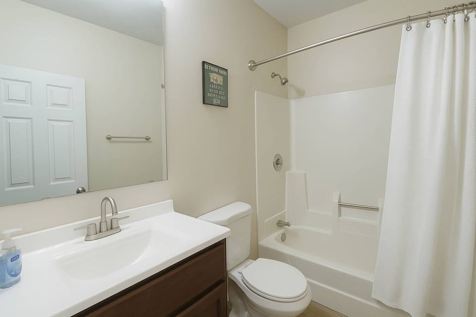 Full bathroom with vanity, mirror, and tub/shower combo.