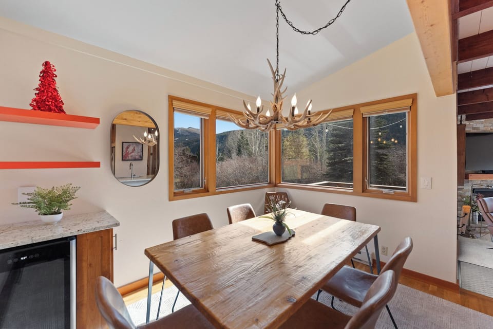 Gather around this warm dining space where rustic charm meets mountain views through expansive windows.