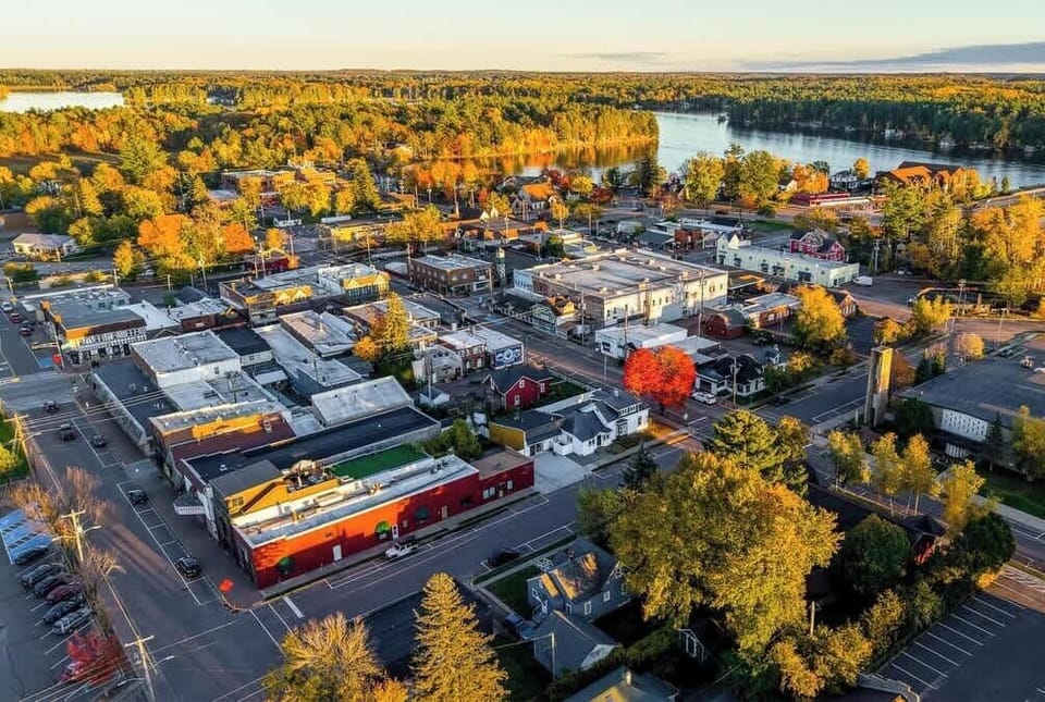 A sweeping aerial view looking toward Lake Minocqua and the bridge, highlighting the cottage’s desirable island location.