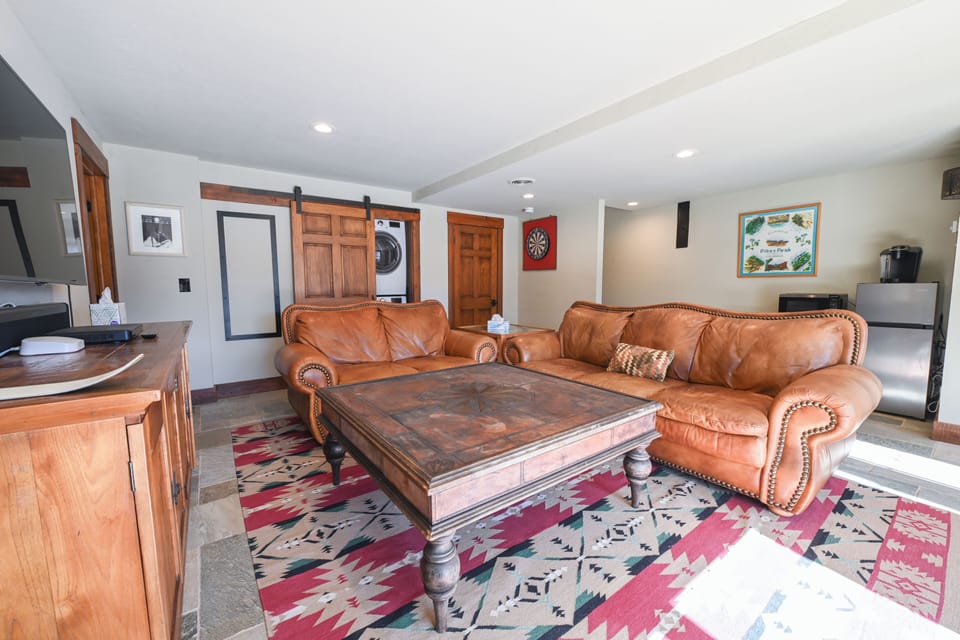 A cozy second living area with plush leather seating, dartboard, and smart TV 
