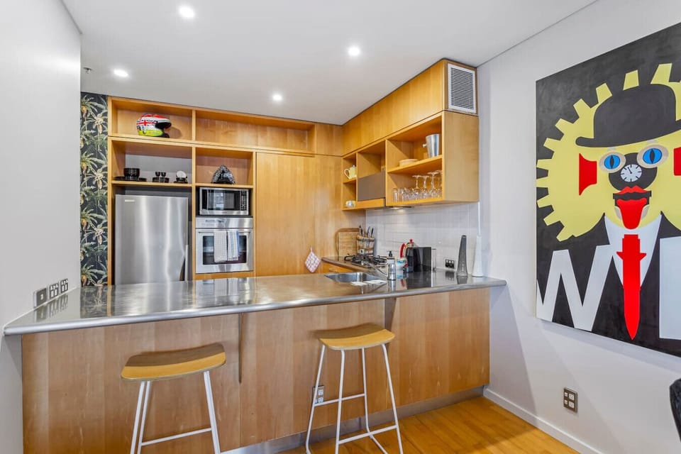 The kitchen up close — warm timber cabinetry, a well-stocked pantry, gas cooking, and a stainless bench that`s seen some good meals. The kind of kitchen you actually want to use
