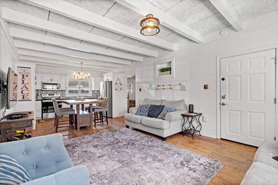 Spacious living room with a plush oversized loveseat, full sofa, cozy chair, and a big-screen Smart TV. Modern décor, open floor plan, and free Wi-Fi create a comfortable space to relax at the beach.