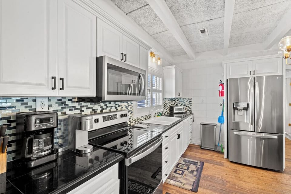 Fully stocked kitchen featuring modern stainless-steel appliances, including a drip and Keurig coffee maker, dishwasher, side-by-side fridge, deep sink, microwave, stove, oven, toaster, and all essentials for easy cooking.