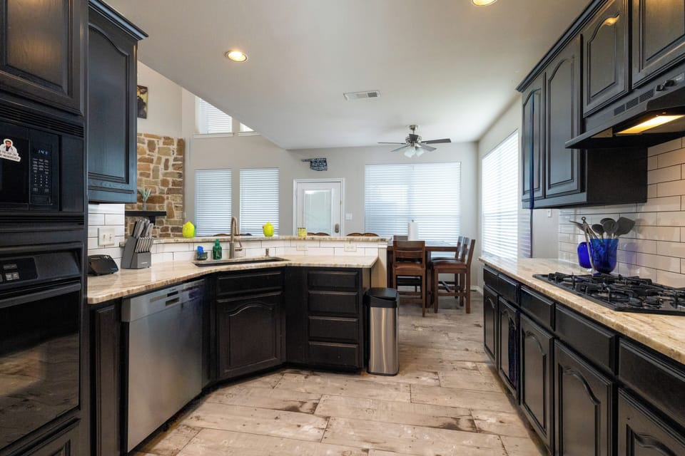 Bright kitchen w/ black cabinets, stainless appliances, and a breakfast bar