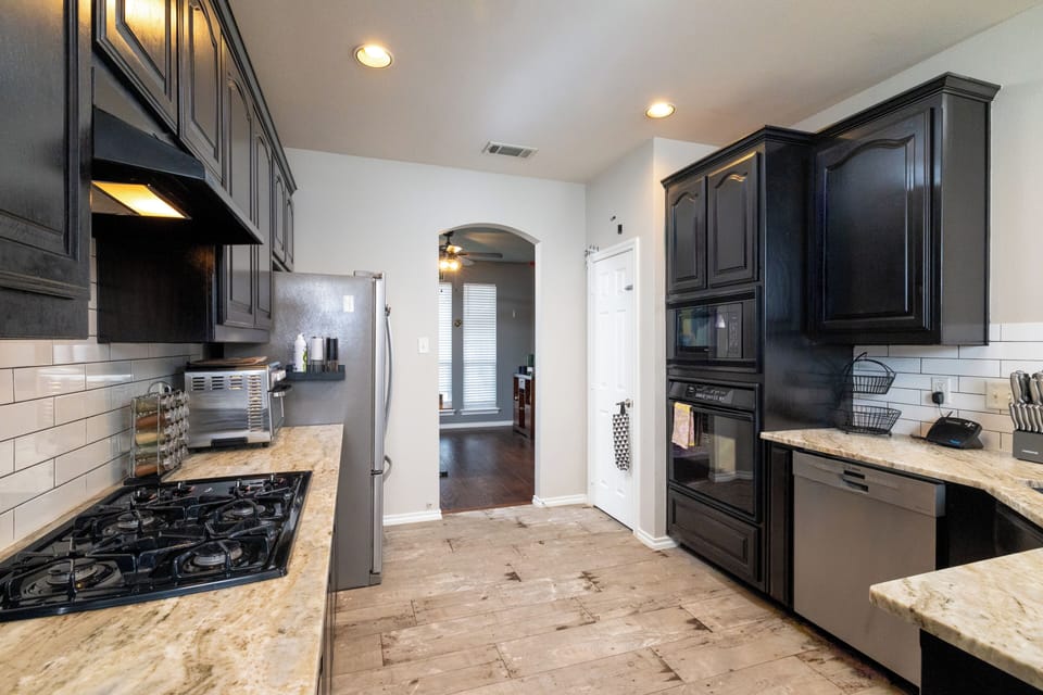 Bright kitchen w/ black cabinets, stainless appliances, and a breakfast bar