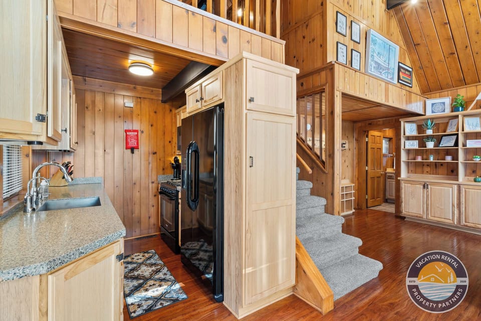 Open-concept comfort: A well-equipped kitchen flows seamlessly into the main living space, with stairs leading to the loft above. Designed for shared meals, easy mornings, and relaxed evenings under one roof.