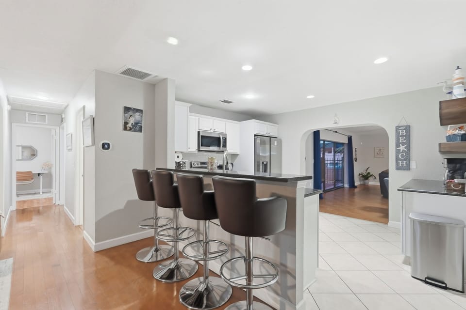 The kitchen features a sleek breakfast bar with four stools, perfect for casual meals or morning coffee.