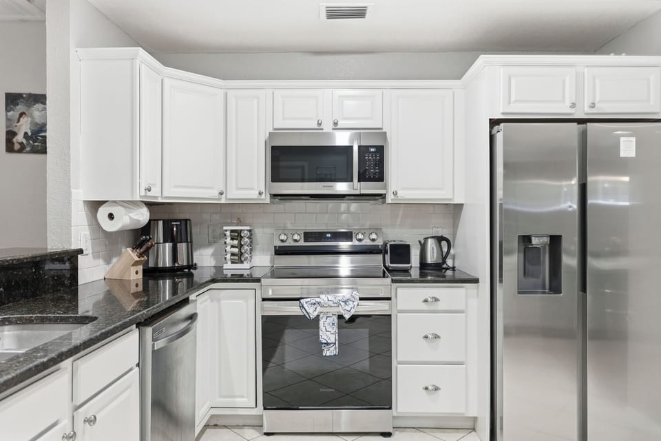 The kitchen is fully equipped with stainless steel appliances, including a refrigerator, oven, and dishwasher, making cooking and meal prep a breeze! 