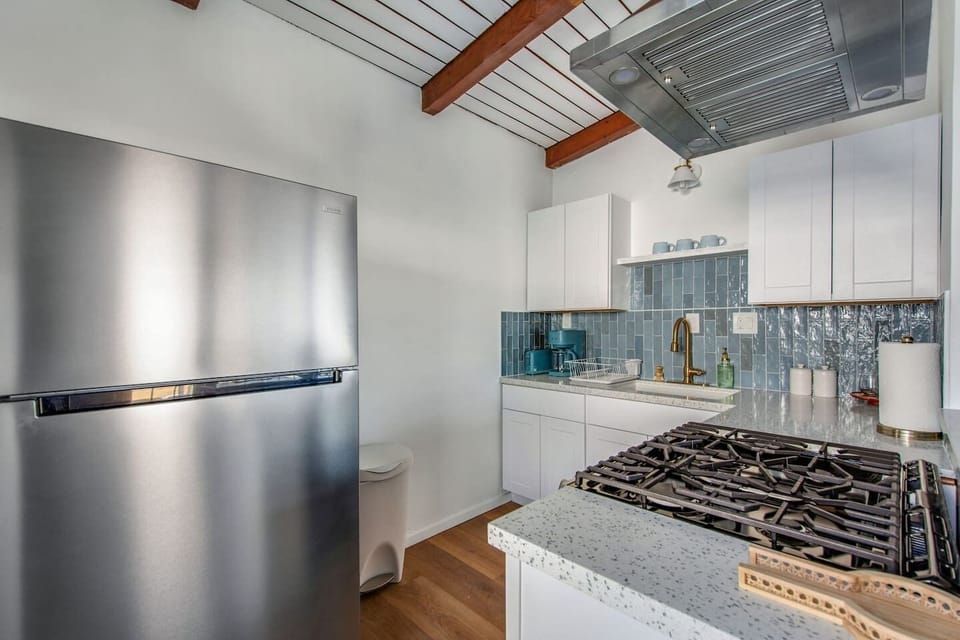 Fully stocked kitchen with stainless steel appliances, coffee maker, and counter seating for two.