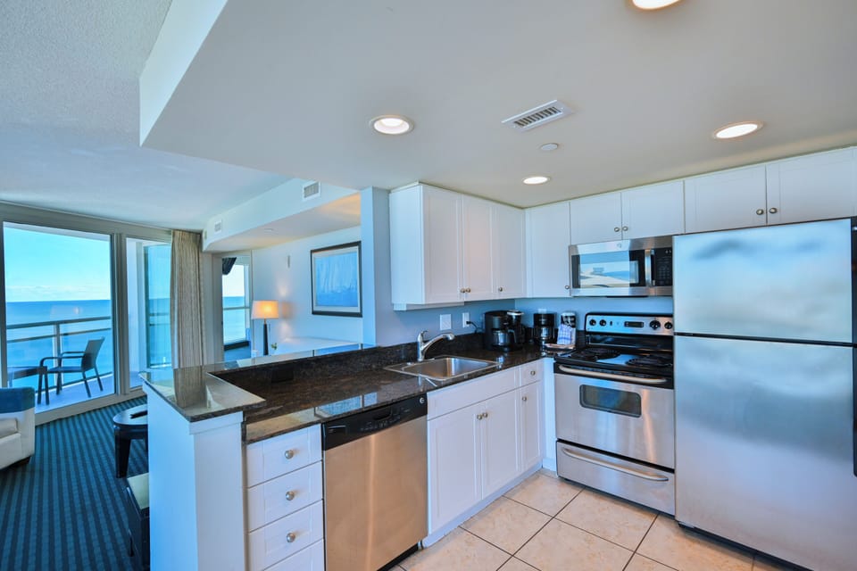 Open kitchen with granite counters and ocean-view balcony